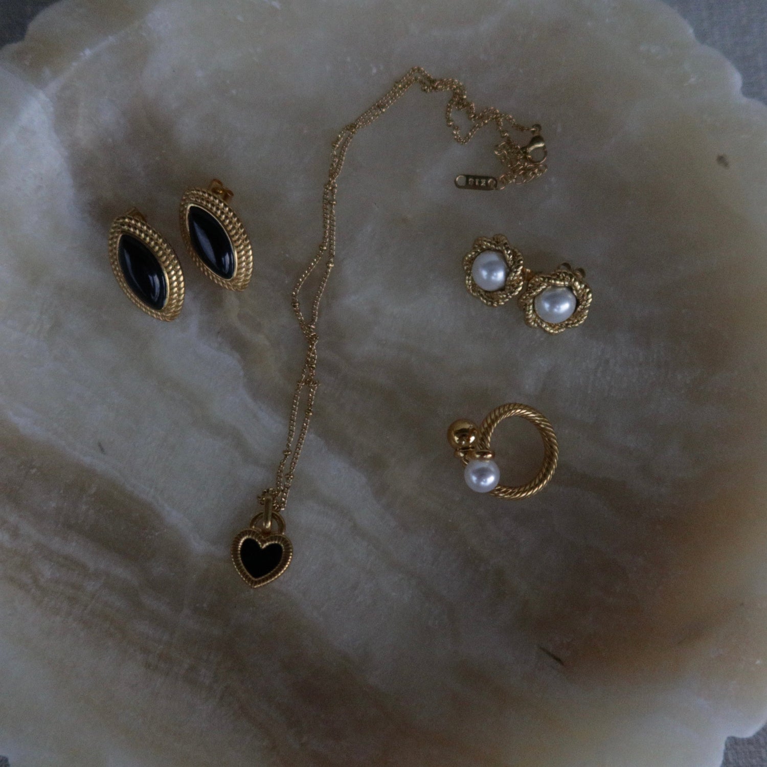 Jewelry set including gold plated earrings BISCUIT, gold plated necklace ALMA and the waterproof gold plated ring SOLARA on a decorative white dish.