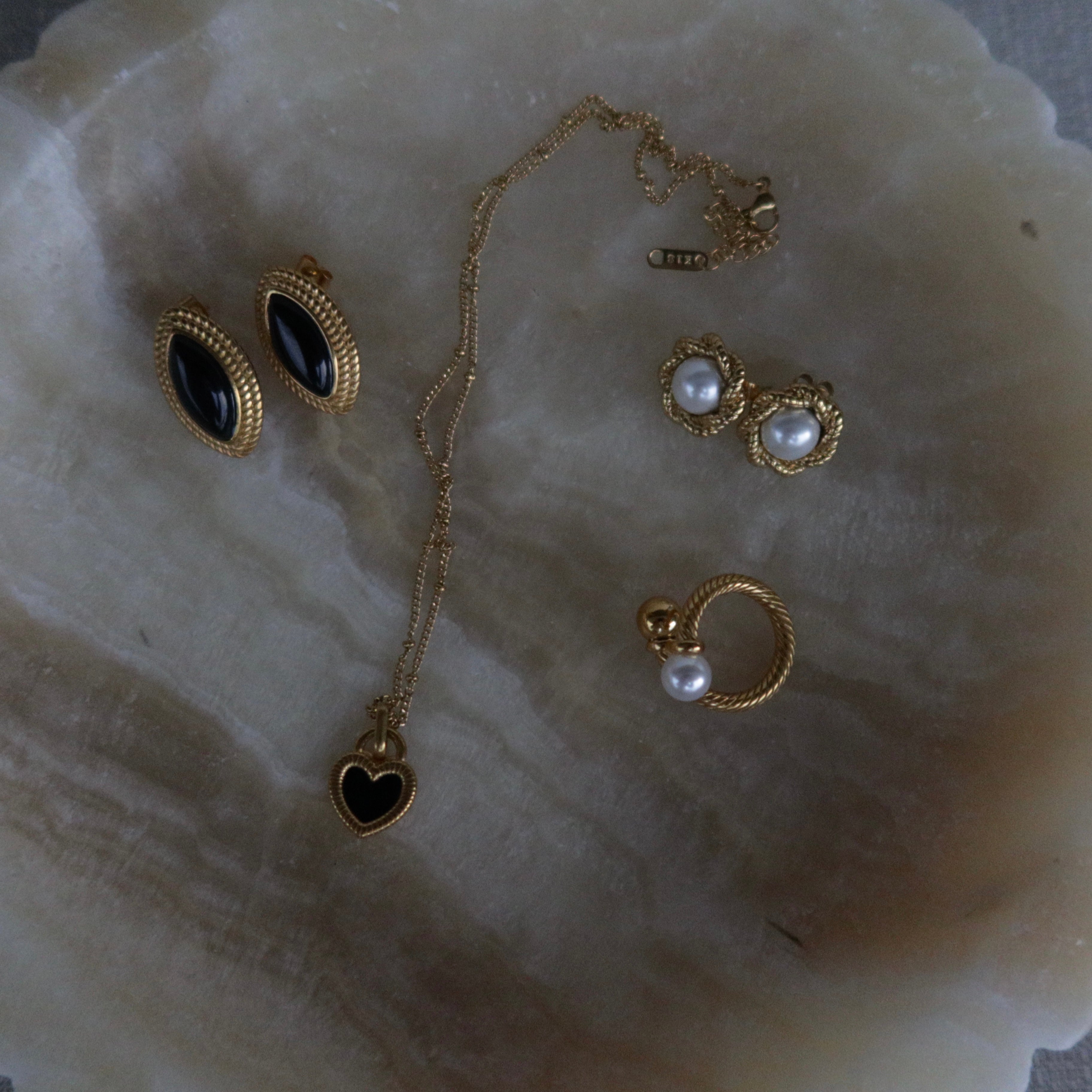 Jewelry set including gold plated earrings BISCUIT, gold plated necklace ALMA and the waterproof gold plated ring SOLARA on a decorative white dish.
